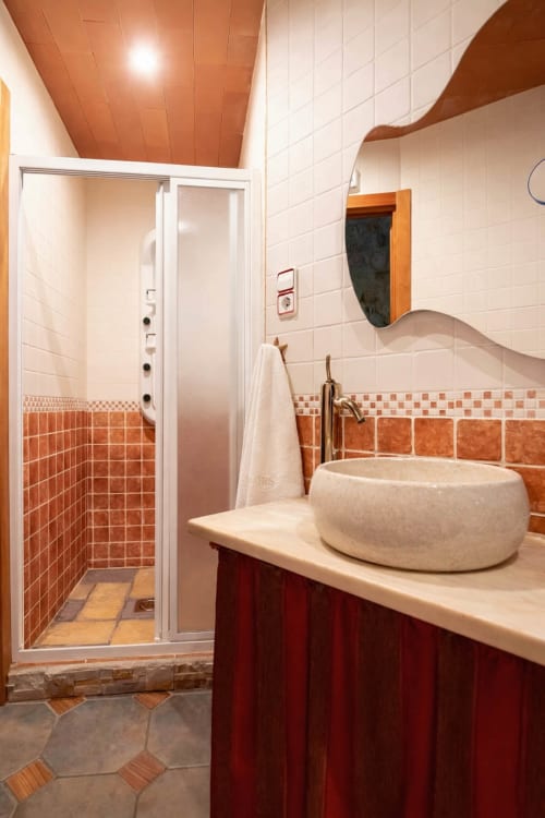 Baño contemporáneo con ducha y acabados cálidos en madera y piedra
