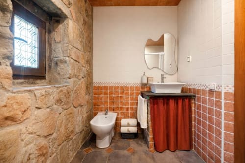 Baño de piedra con ventana medieval y acabados contemporáneos