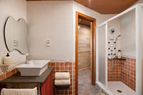 Baño amplio con ducha y acabados cálidos en una fortaleza histórica cerca de Barcelona