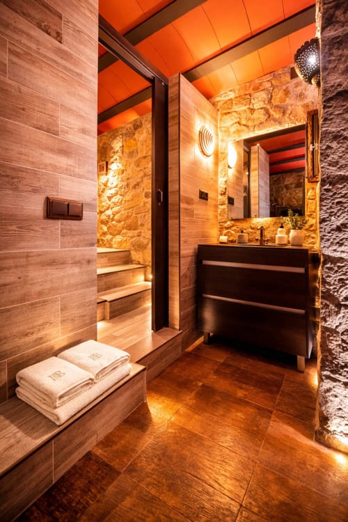 Baño contemporáneo de piedra con iluminación cálida y diseño integrado