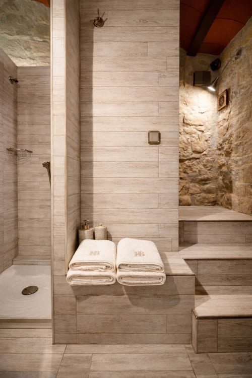 Baño contemporáneo con acabados en madera y paredes de piedra