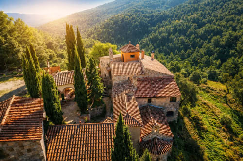 Vista aérea de edificios de piedra y tejados tradicionales rodeados de bosque en el Moianès