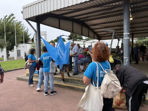 Community event at Golden Mermaid Villa in Ribeirinha with volunteers in blue shirts under a metal canopy