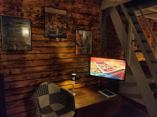 Rustic wooden room at Les Troglos de Beaulieu with TV, chair, and framed inspirational wall art