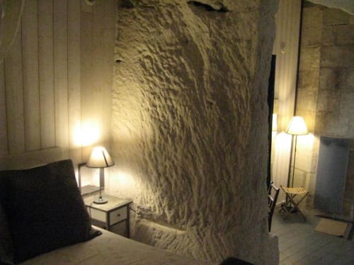 Cozy troglodyte bedroom at Les Troglos de Beaulieu with stone walls, ambient lighting, bedside lamp, and rustic charm in