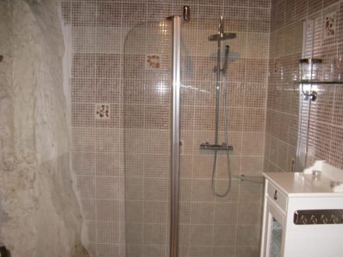 Modern bathroom with beige mosaic tile shower enclosure and rainfall showerhead at Les Troglos de Beaulieu
