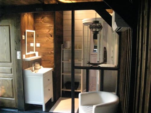 Salle de bain moderne aux Troglos de Beaulieu avec douche vitrée, vasque blanche et mur d'accent bois dans La Cabane