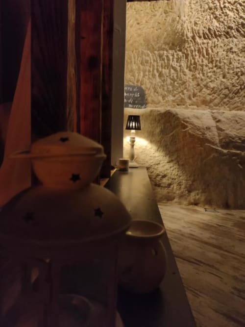 Cozy troglodyte room at Les Troglos de Beaulieu with rustic stone walls, warm lamp lighting, and wooden flooring in historic