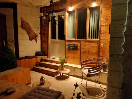 Patio rustique des Troglos de Beaulieu avec portes en bois, mobilier extérieur et vue sur le jardin la nuit