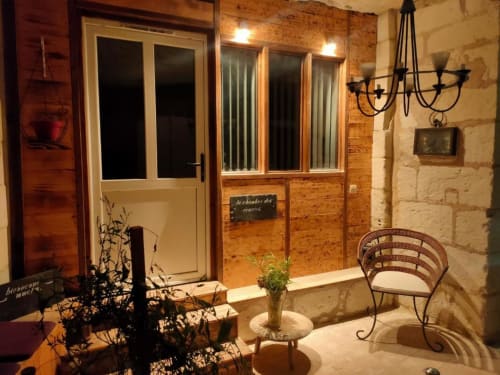 Terrasse de cour en pierre aux Troglos de Beaulieu avec mobilier en fer forgé et éclairage ambiant