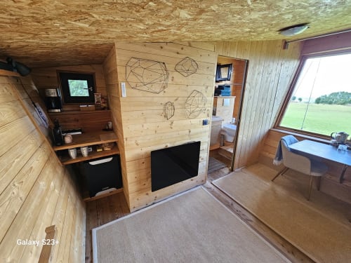 Intérieur en bois de la chambre La Poupe au Logis Las Crozas avec kitchenette, TV, salle de bain et vue sur la campagne près de Vernines
