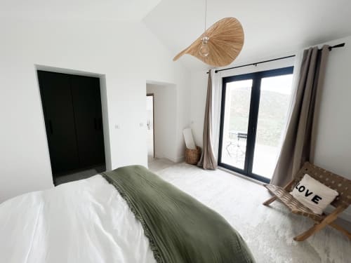 Chambre moderne de l'hôtel Anne Duval à Saint Florent avec lit, armoire noire, portes vitrées sur terrasse et plafond tressé