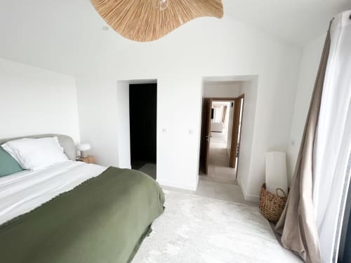 Chambre moderne de l'hôtel Anne Duval à Saint-Florent avec literie verte, décor minimaliste et plafond en bois naturel