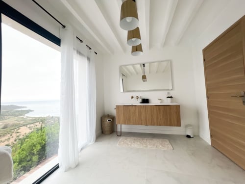 Salle de bains moderne de l'hôtel Anne Duval à Saint-Florent avec vue côtière, vasque en bois et lumière naturelle abondante