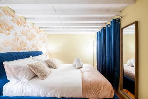 Camera moderna presso Bronze Horse Affittacamere a Firenze con letto rivestito blu, pareti color crema e tonalità gialle