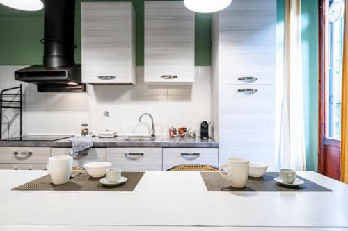 Cucina moderna della Bronze Horse Affittacamere con mobili bianchi, tavolo da pranzo e pareti verdi a Firenze