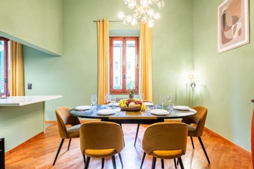 Sala da pranzo moderna del Bronze Horse BnB Firenze con pareti verdi, sedie color senape e elegante tavolo preparato