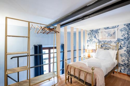Elegante camera da letto presso Bronze Horse Affittacamere a Firenze con letto in ottone, carta da parati floreale blu e divisorio moderno