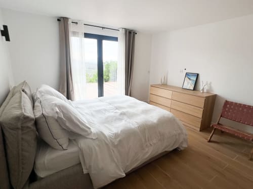 Chambre moderne de l'hôtel Anne Duval à Saint-Florent avec literie blanche, mobilier en bois et accès à la terrasse