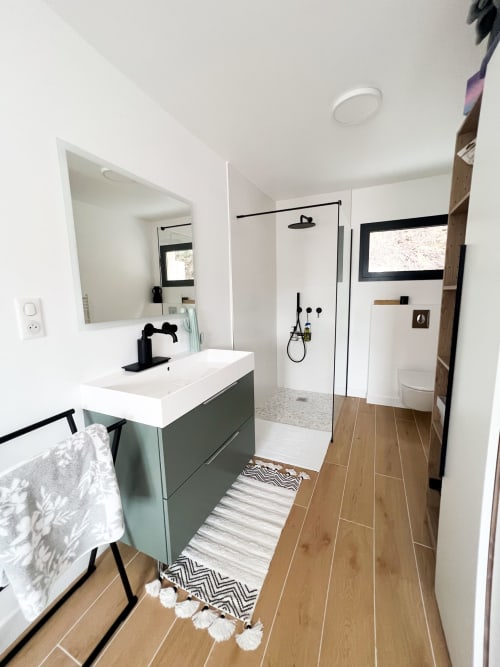 Salle de bain moderne à l'hôtel Anne Duval à Saint-Florent avec meuble vasque vert sauge, douche spacieuse et revêtement imitation bois