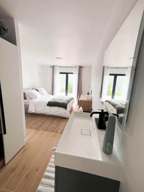 Salle de bain moderne attenante à la chambre avec lavabo blanc et miroir à l'hôtel Anne Duval à Saint-Florent