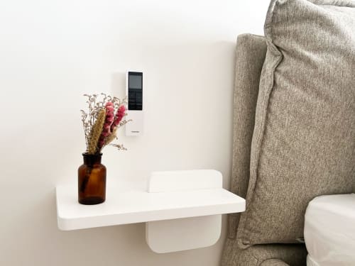 Fauteuil beige avec étagère flottante blanche, vase ambré aux fleurs séchées, et thermostat numérique à l'hôtel Anne Duval à Saint
