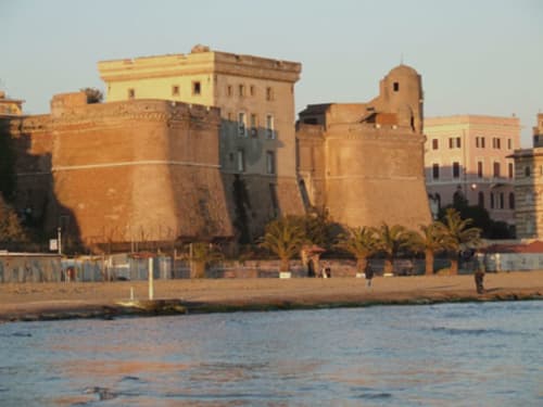 Fortezza storica sul lungomare di Nettuno con architettura tradizionale e palme lungo la spiaggia