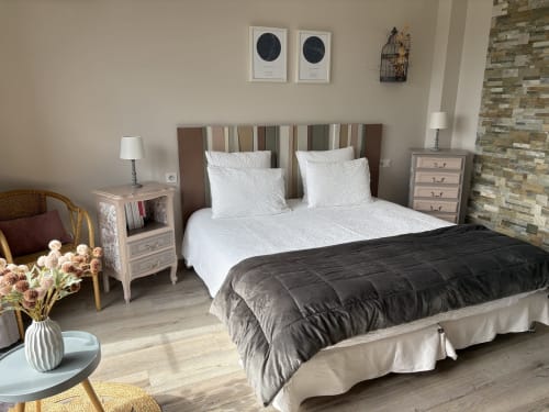 La chambre Céleste aux Etoiles de Calès, avec un lit à tête de lit rayée, draps blancs et mur en pierre apparente