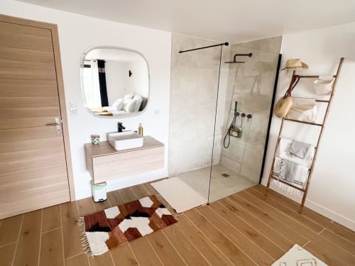 Salle de bain moderne de l'hôtel Anne Duval à Saint Florent avec douche ouverte, meuble vasque en bois et sèche-serviettes chauffant