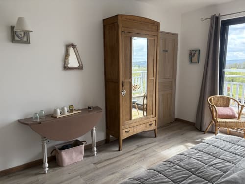Chambre spacieuse aux Etoiles de Calès avec armoire en bois, vue sur balcon et fauteuil en rotin à Calès
