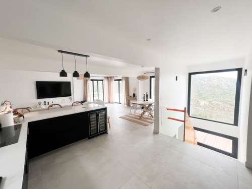 Cuisine ouverte et salon contemporain à l'hôtel Anne Duval à Saint-Florent avec luminaires noirs et grandes baies vitrées