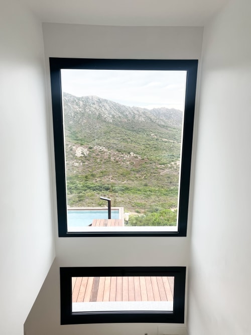 Vue sur les montagnes depuis la fenêtre de l'hôtel Anne Duval, Saint-Florent, avec colline verdoyante et terrasse en bois