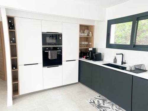 Cuisine moderne de l'hôtel Anne Duval à Saint-Florent avec meubles bicolores, électroménagers intégrés et îlot avec évier.