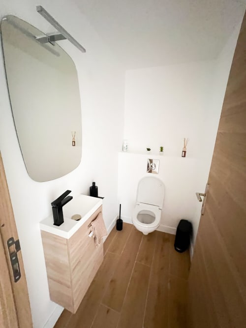 Salle de bains moderne à l'hôtel Anne Duval à Saint-Florent avec lavabo, toilettes, miroir et sol en bois