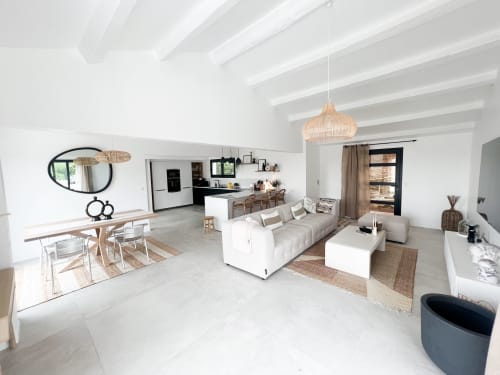 Spacieux séjour ouvert de l'hôtel Anne Duval à Saint-Florent avec poutres blanches, salle à manger, canapé et cuisine