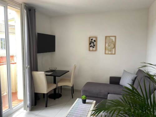 Élégant salon moderne à la Résidence Kimi Cannes avec canapé, table à manger, TV et balcon avec vue sur le jardin