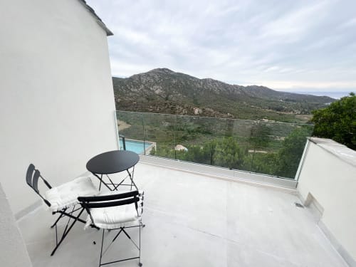 Terrasse moderne de l'hôtel Anne Duval à Saint-Florent avec vue sur les montagnes, espace de détente et balustrades en verre