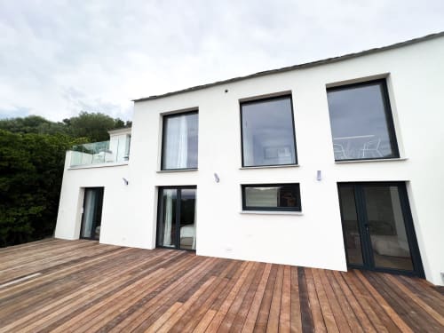 Bâtiment blanc contemporain de l'hôtel Anne Duval à Saint-Florent avec terrasse bois et baies vitrées à cadres noirs