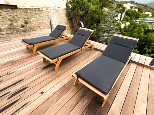Trois chaises longues en bois avec coussins noirs sur une terrasse en bois à l'hôtel Anne Duval à Saint-Florent, vue sur