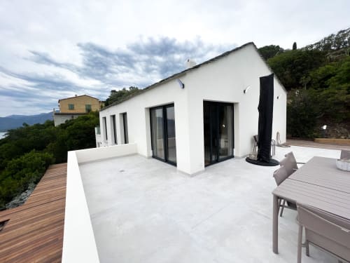 Terrasse moderne de l'hôtel Anne Duval à Saint-Florent avec bâtiment blanc, terrasse en bois et vue sur les montagnes