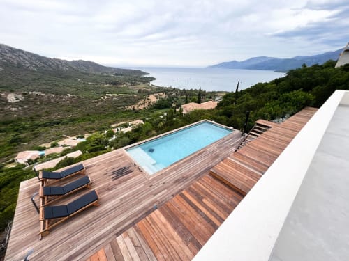 Piscine  surplombant la baie de Saint-Florent, eau turquoise, terrasse en bois, chaises longues