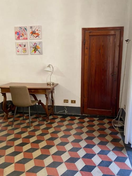 Modern workspace at Bronze Horse Affittacamere in Florence with wooden desk, geometric floor tiles, and abstract wall art