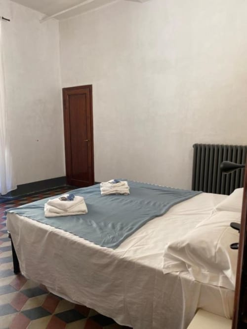 Simple bedroom at Bronze Horse Affittacamere in Florence with bed, wooden door, radiator, and tiled floor