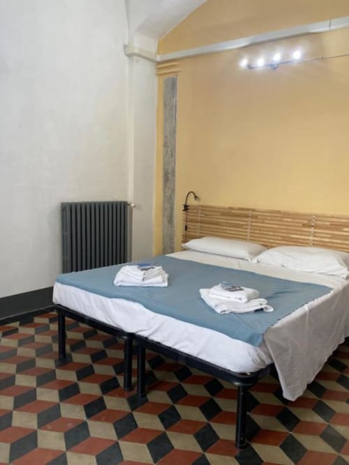 Cozy bedroom at Bronze Horse Affittacamere in Florence with wooden bed headboard, blue bedding, and geometric floor tiles