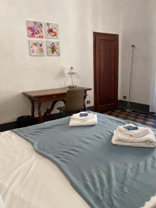 Habitación en Bronze Horse Affittacamere en Florencia con cama, escritorio, lámpara y arte colorido en la pared