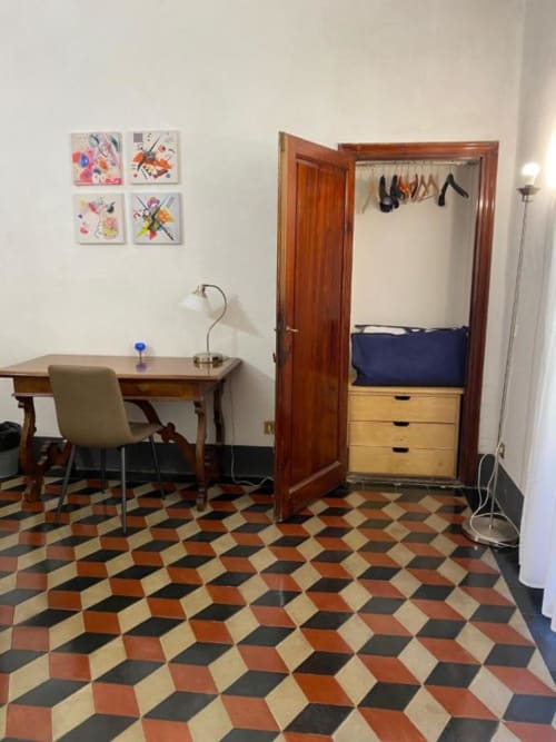 Acogedora habitación en Bronze Horse Affittacamere en Florencia con piso geométrico, escritorio, armario de madera y arte mural colorido