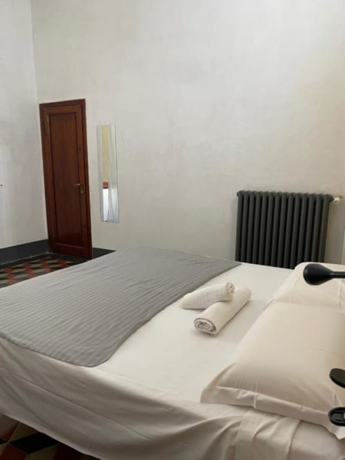 Camera pulita presso Bronze Horse Affittacamere con letto, asciugamani, radiatore e porta in legno a Firenze