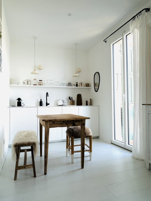 Bright modern kitchen-dining area in Casa di Bastia apartment with wooden table, white cabinetry, and sea view doors