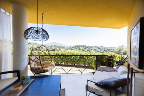Terraza de BH Marbella con silla colgante, techo amarillo, vistas al valle y mobiliario moderno
