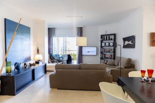 Salón moderno del hotel BH Marbella con sofá marrón, muebles azules y vistas al océano